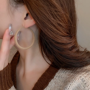 Detail of matte beige flocking hoop earring worn by a model with long brown hair