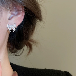 Close-up of bow knot stud earrings featuring a white pearl and sparkling crystals