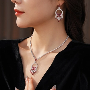 Close-up of butterfly droplet necklace and earrings set with red and clear crystals
