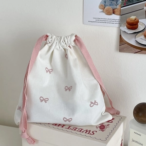 Detail of pink bow print on off-white canvas drawstring bag with rope closure