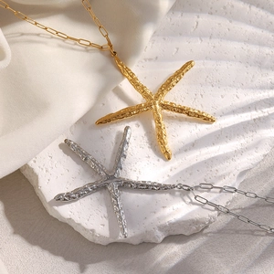 Detailed view of gold and silver starfish pendants with textured finish on paperclip chains