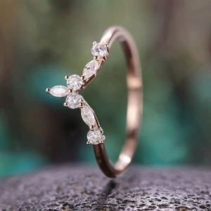 Makro-Detail eines roségoldenen V-Rings mit Zirkonia im Marquise-Schliff auf dunklem Stein