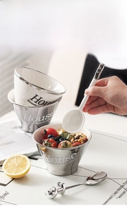 Detail of luxury ceramic bowl with silver rim and cute bear handle spoon on a table