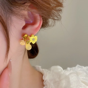 Close-up of yellow flower stud earrings with cat eye stone and cubic zirconia on model