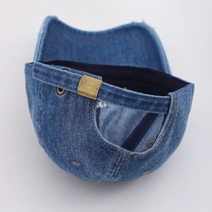 Detail der verstellbaren Bronzeschnalle und gewaschenen Denim-Textur der Baseballkappe