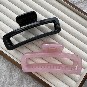 Flat lay of black and translucent pink square hair claw clips on a jewelry tray
