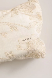 Détail de la broderie florale sur la trousse de toilette en lin beige