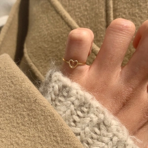 Macro shot of minimalist hollow heart-shaped gold ring worn on toe for styling