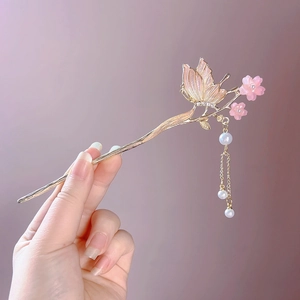 Détail d'un pic à cheveux papillon doré avec fleurs roses et glands en perles