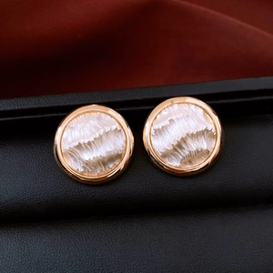 Détail macro de boucles d'oreilles dorées 16K avec texture perle blanche sur cuir noir