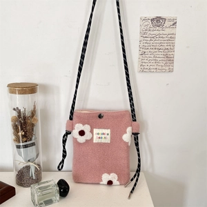 Detail of pink faux fur crossbody bag with daisy applique and woven strap