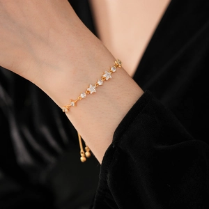 Detail of adjustable gold star bracelet with sparkling cubic zirconia on a model's wrist