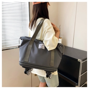 Detailed view of the grey foldable travel bag with spinner wheels shown in a lifestyle setting
