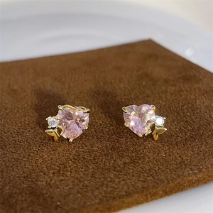 Macro shot of pink heart-shaped crystal earrings with golden butterfly and diamond accents