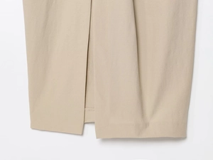 Detailed view of the side slit and fine stitching on a beige midi dress woven fabric