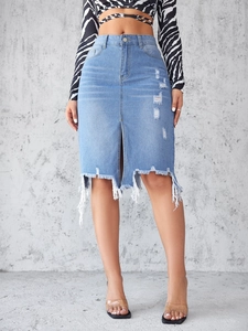 Close-up of distressed denim skirt showing ripped holes and raw fringe hem details