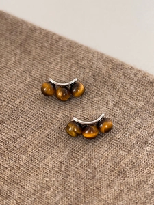 Macro shot of tiger eye stone earrings on brown knit fabric showing natural textures