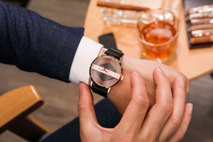 Close-up of TOMI business watch featuring a rose gold skeleton dial and black leather strap