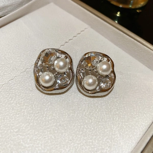 Detail of silver irregular oval stud earrings with pearls and crystals in a box
