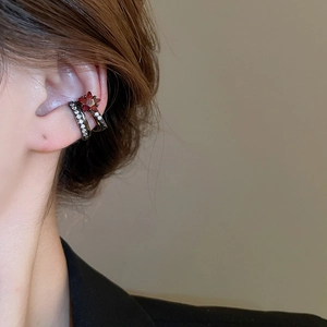 Détail de la bague d'oreille double noire avec strass brillants et étoile rouge sur l'oreille
