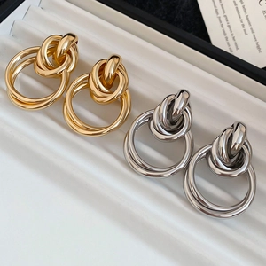 Vue détaillée de boucles d'oreilles nœuds entrelacés dorées et argentées sur un plateau