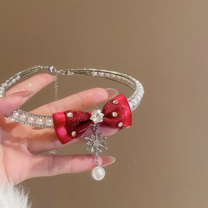 Macro view of double-layer necklace with red bow, snowflake charm and elegant pearls