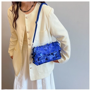 Detailed view of deep blue sequin shoulder bag with adjustable strap on a female model