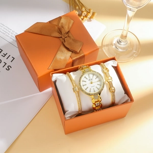 Close-up of golden diamond-encrusted women's watch and bracelet set in orange gift box
