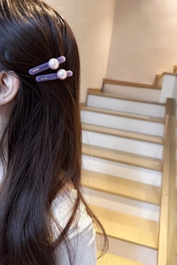 Close-up of elegant purple pearl hair clips worn on side by a woman with long hair