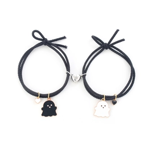 Close-up of black braided couple bracelets with heart magnets and ghost charms