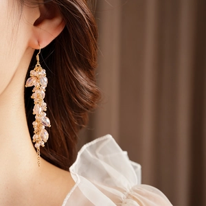 Detail of bohemian gold tassel earrings with champagne crystal beads on a model