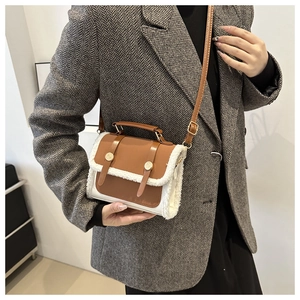 Detail of crossbody bag with brown leather and white shearling trim on grey blazer
