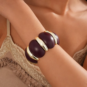 Detail of wide retro acrylic and gold metal bangle on wrist with bohemian style