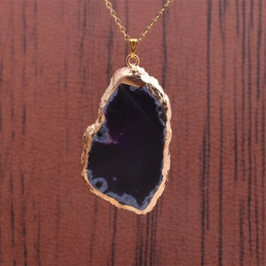 Vue détaillée d'un pendentif en agate violette naturelle avec bords dorés sur chaîne
