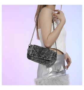 Vista laterale della modella con borsa in denim grigio slavato e catena argentata
