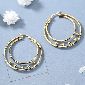 Chic 3.5cm double hoop golden earrings with small beads on a light blue fabric background