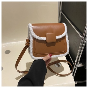 Close-up of brown leather crossbody bag with white sherpa trim and adjustable strap
