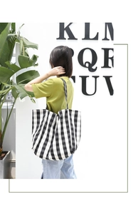 Classic black and white checkered canvas tote bag shown worn on shoulder for daily commute