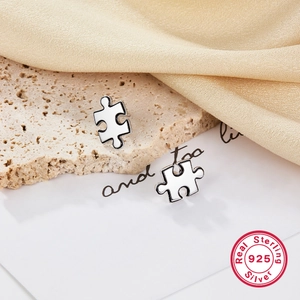 Minimalist S925 sterling silver puzzle stud earrings on elegant silk and stone background