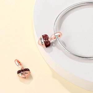 Macro shot of rose gold heart-shaped chocolate charm with text on silver snake chain