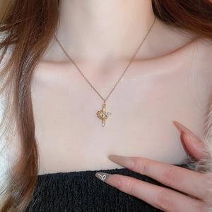 Dettaglio di una collana con ciondolo a croce dorata con zirconi scintillanti su modella