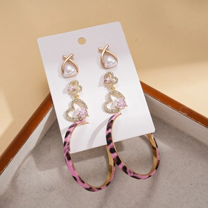 Detailed set of gold earrings with pearls, pink hearts, and leopard print hoops