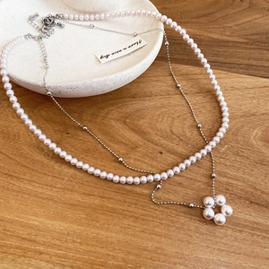 Detail of a layered pearl necklace with a floral pearl pendant on a ceramic tray