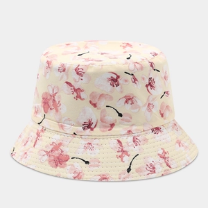 Close-up of pink cherry blossom print on a beige cotton reversible bucket hat fabric