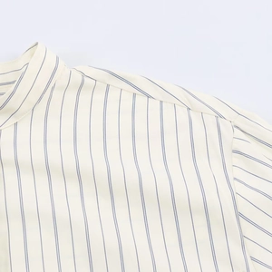 Detailed close-up of stand-up collar and blue pinstripe pattern on cotton linen shirt