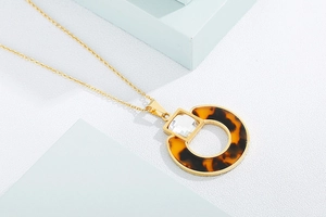 Detail of vintage gold necklace with crystal pendant and tortoise shell resin ring