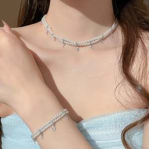 Model wearing double-layer pearl necklace and bracelet set with teardrop zircon charms