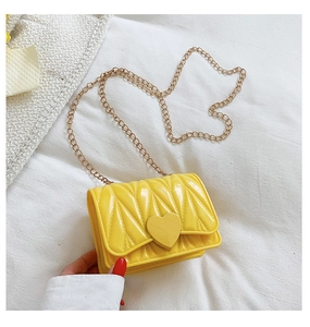 Detail of yellow heart-shaped mini bag with matelassé texture and gold chain strap