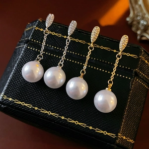 Detailed view of silver and gold pearl earrings with zircon inlay on vintage jewelry box