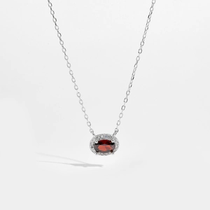 Detail of s925 silver necklace featuring an oval red zircon pendant with a halo of white stones